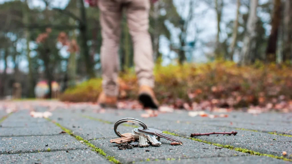 Person looking for lost keys on the ground near their car